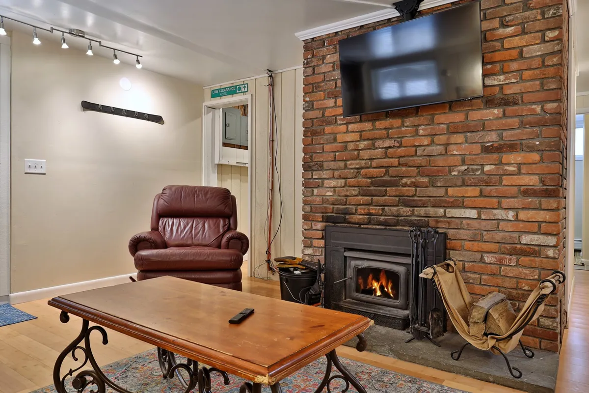 This scene offers a close-up of a brick fireplace with a leather armchair and a wooden coffee table nearby, creating a cozy nook perfect for movie nights or quiet relaxation. The setup naturally invites conversation or unwinding after an active day.