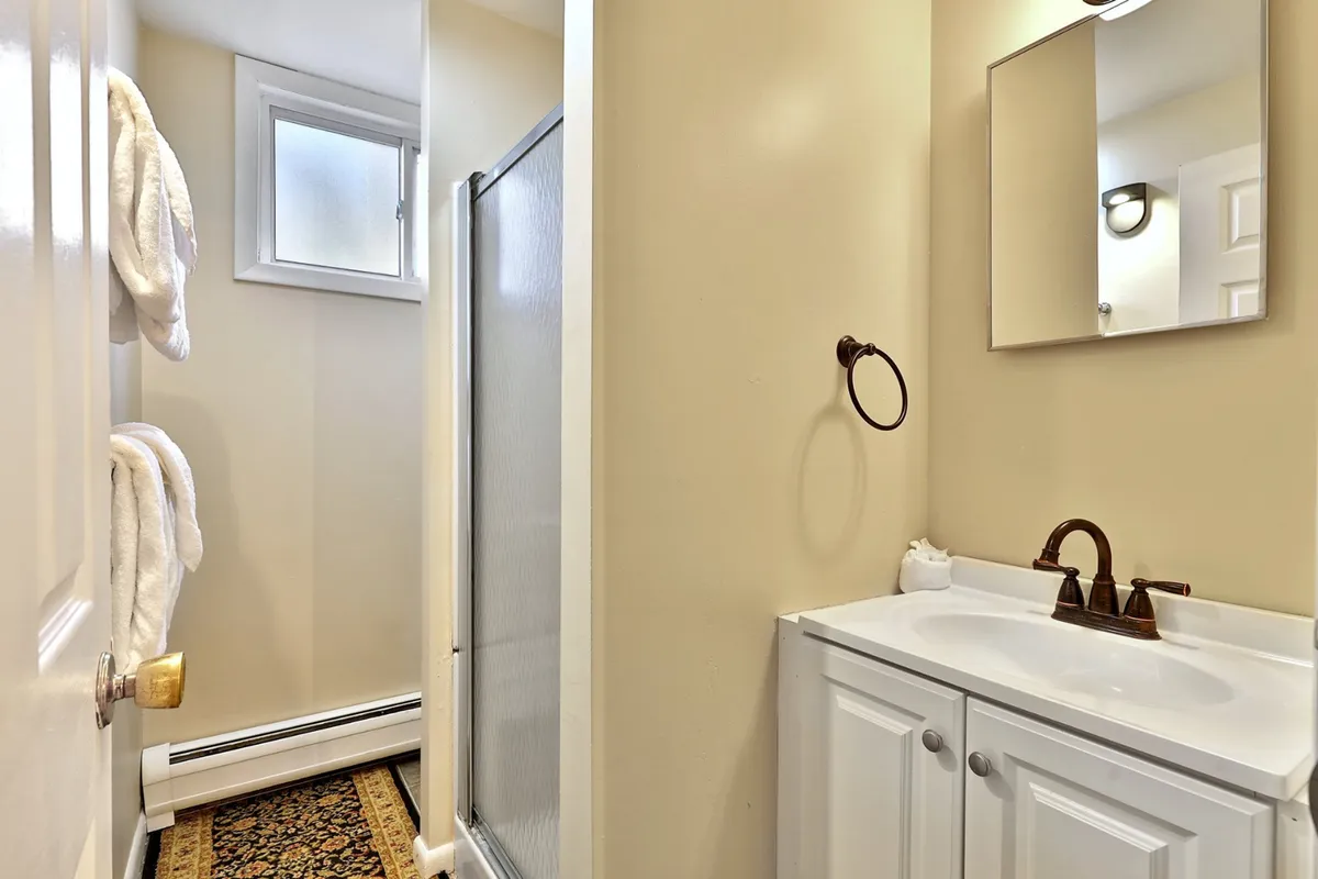 A tidy bathroom with a modern vanity, spacious shower stall, large mirror, and a towel rack. The clean lines and uncluttered space evoke a sense of freshness and rejuvenation.