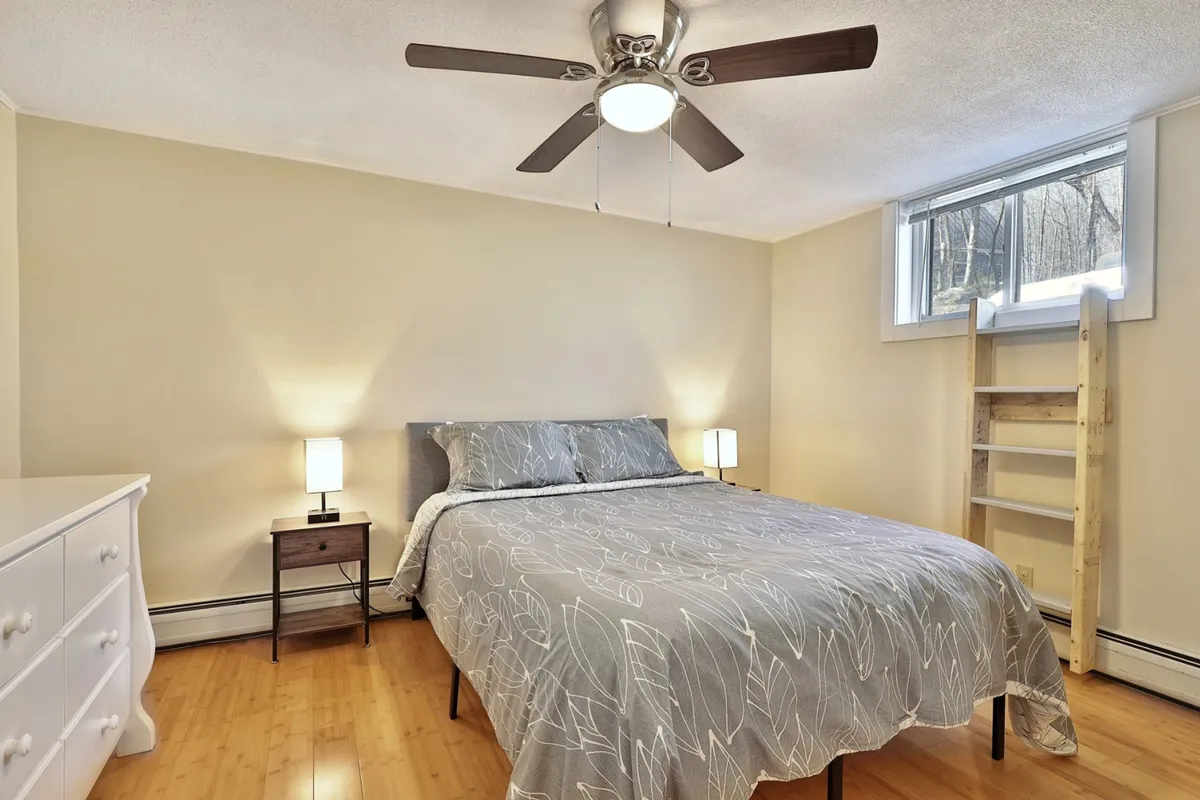 This image features a tranquil bedroom with a neatly made bed, a nightstand, and soft lighting from the fixtures. The room exudes a quiet, restful atmosphere that invites relaxation and comfort.