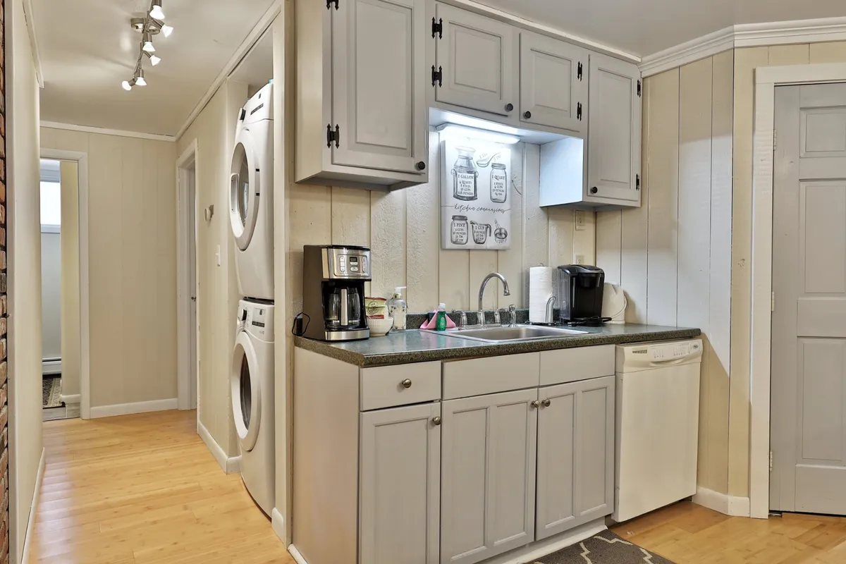The image captures a practical laundry area featuring a washer and dryer, a sink, and homey decorative touches. It conveys convenience and the ability to keep gear clean after outdoor adventures.