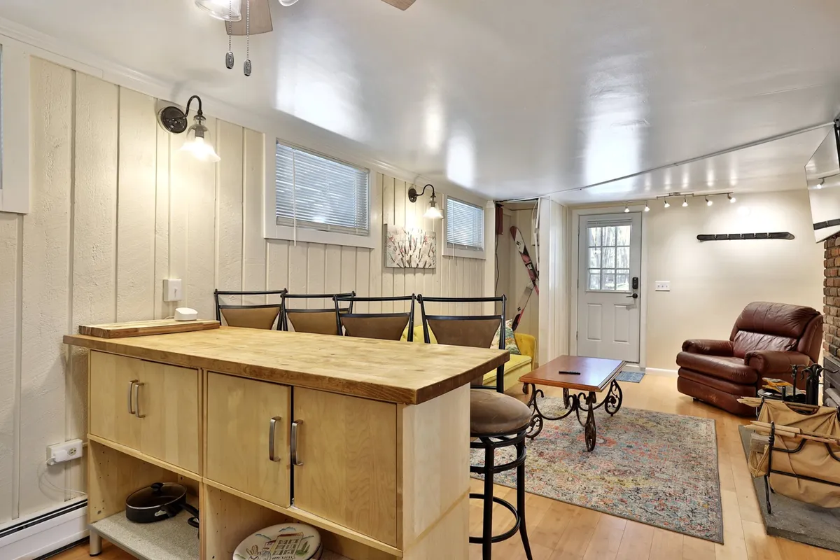 Here, a wooden countertop with bar stools offers a cozy spot for morning coffee or casual snacks. The scene includes a reclining chair and a touch of art on the wall, adding to the inviting atmosphere. This area encourages socializing, cooking, and relaxing, underscoring the kitchen's role as a gathering spot.